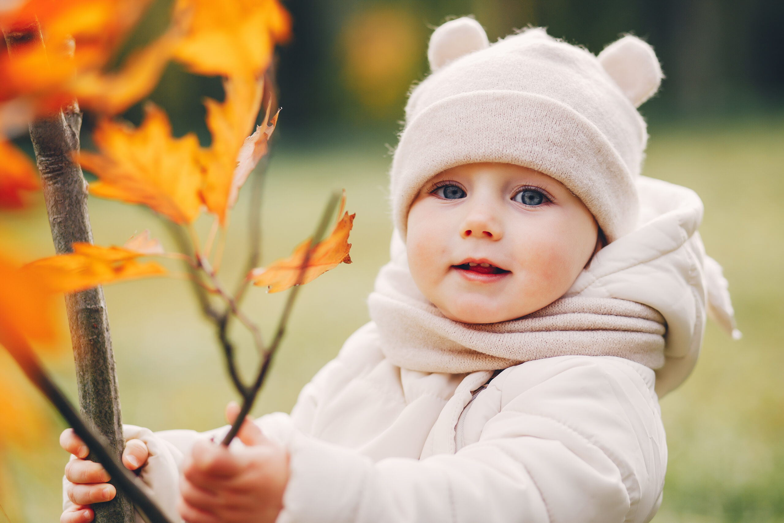 Cute little girl in a autumn park. Child in a white jacket and white hat